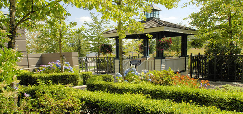 Gazebo surrounded by green trees and manicured shrubs